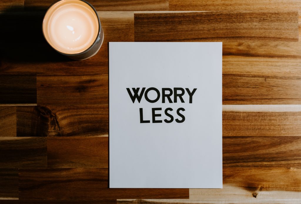 paper that says "worry less" with a candle