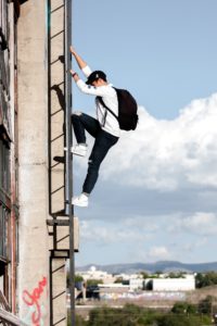 man climbing a ladder on a side of a building